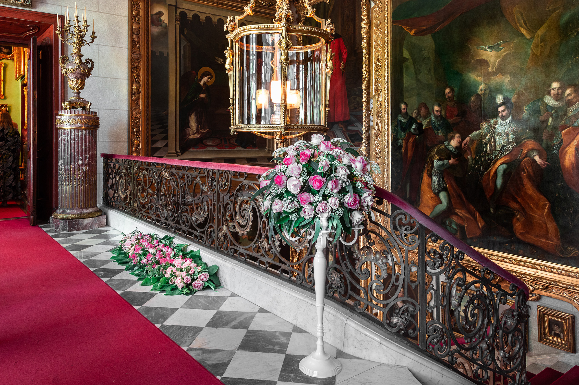 Klatka schodowa pałacu Zamoyskich w Kozłówce, na pierwszym planie kompozycja kwiatowa.